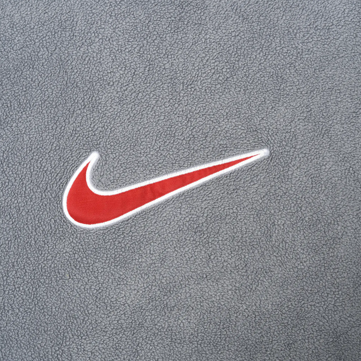 Close-up of red and white Nike Swoosh embroidery on grey fleece