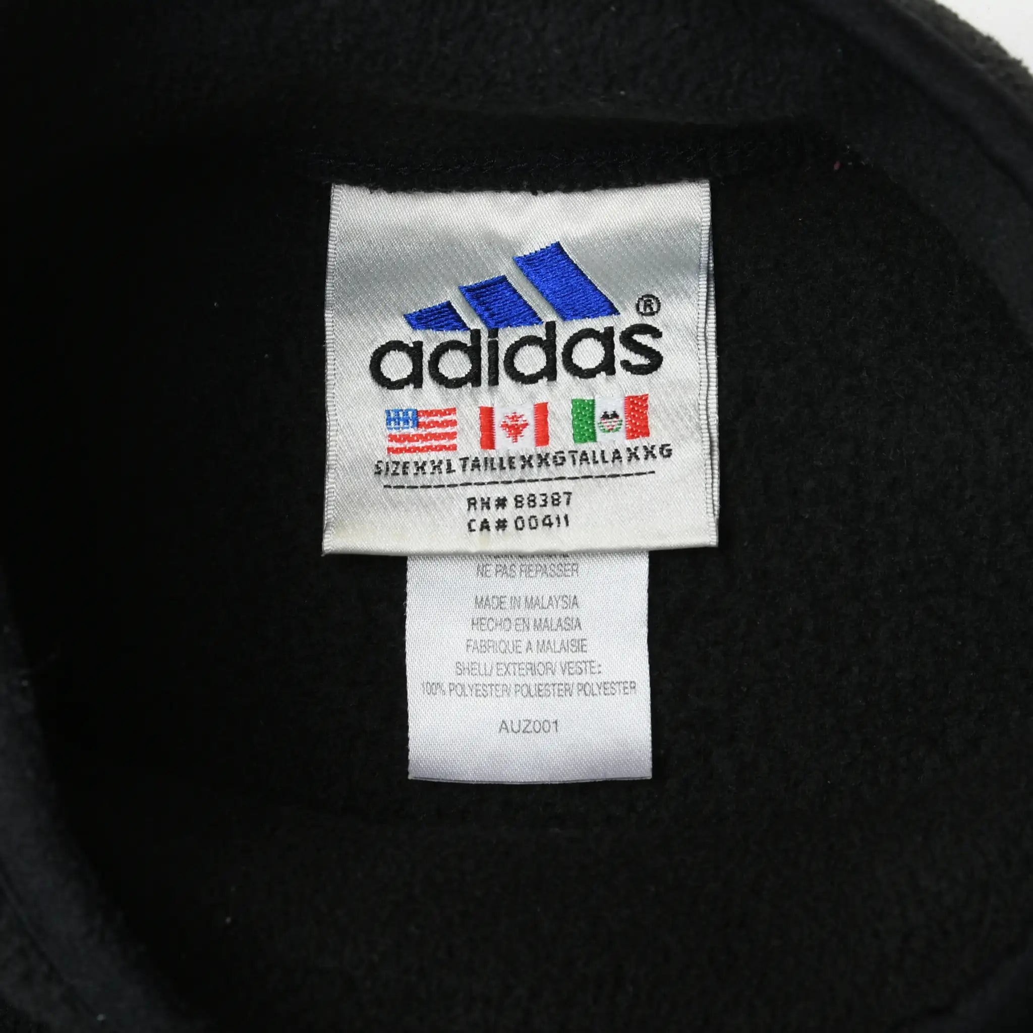 Close-up of adidas neck and care labels inside black fleece turtleneck sweatshirt