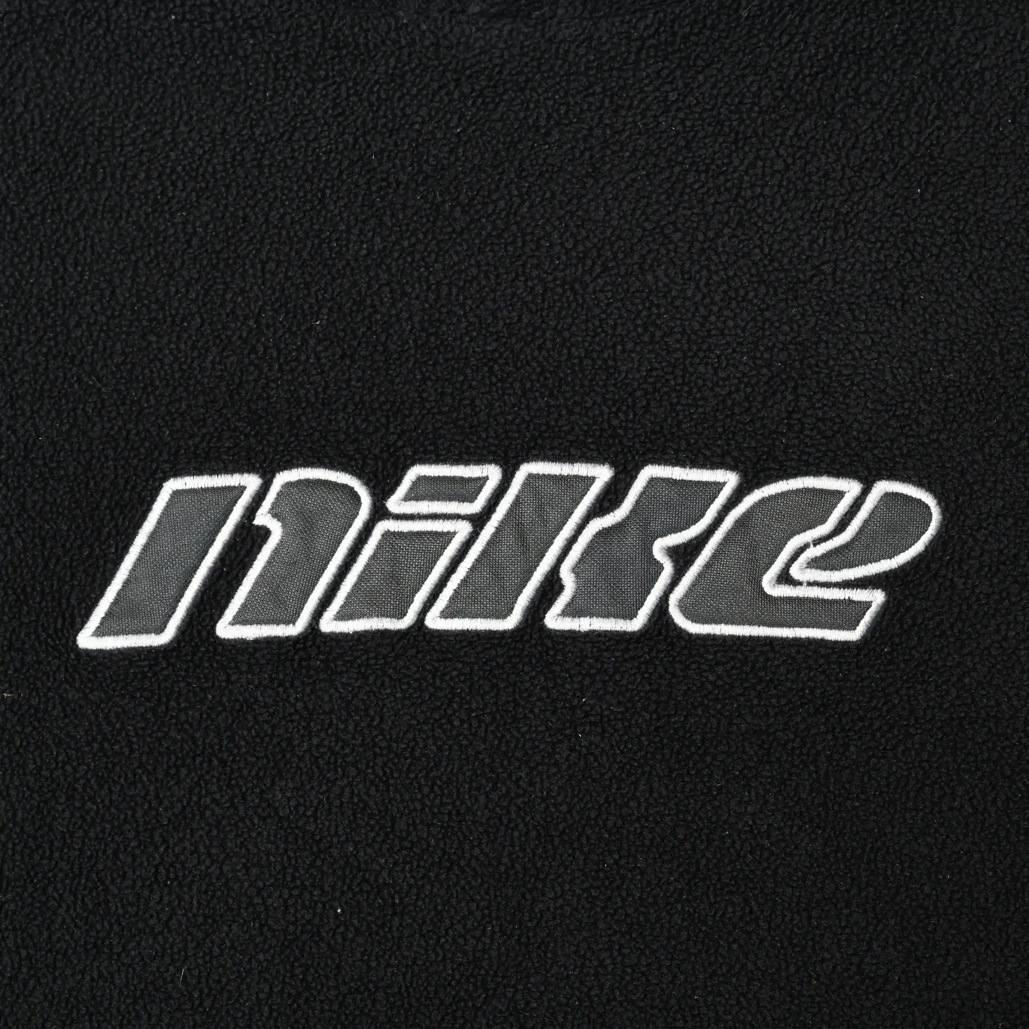 Close-up of outlined Nike spellout embroidery on black fleece