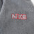 Close-up of red and white Nike wordmark embroidery on grey fleece sleeve
