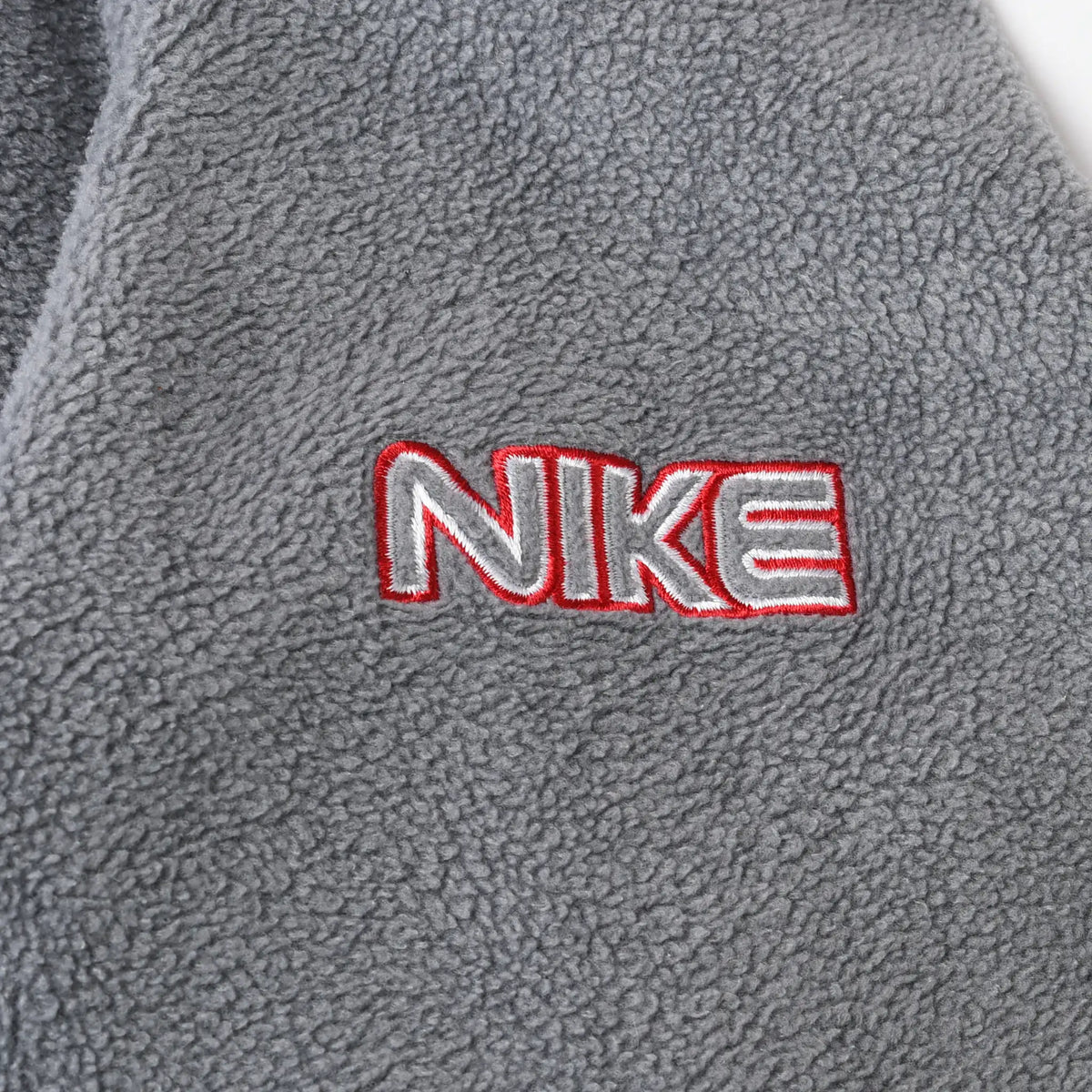 Close-up of red and white Nike wordmark embroidery on grey fleece sleeve