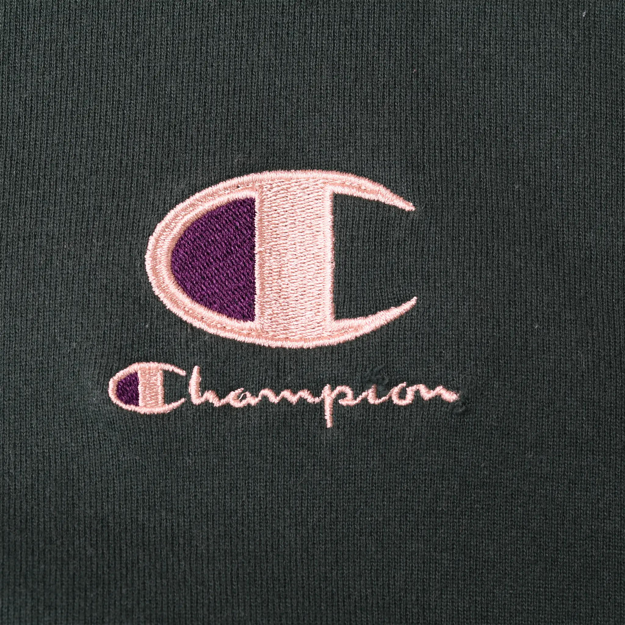 Close-up of pink and purple Champion logo embroidery on dark green fabric