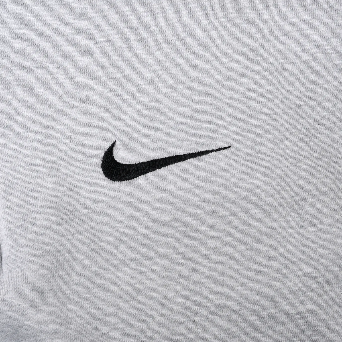 Close-up of black Nike Swoosh embroidery on grey hoodie chest