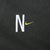 Close-up of white N and lime Nike Swoosh embroidery on dark green chest