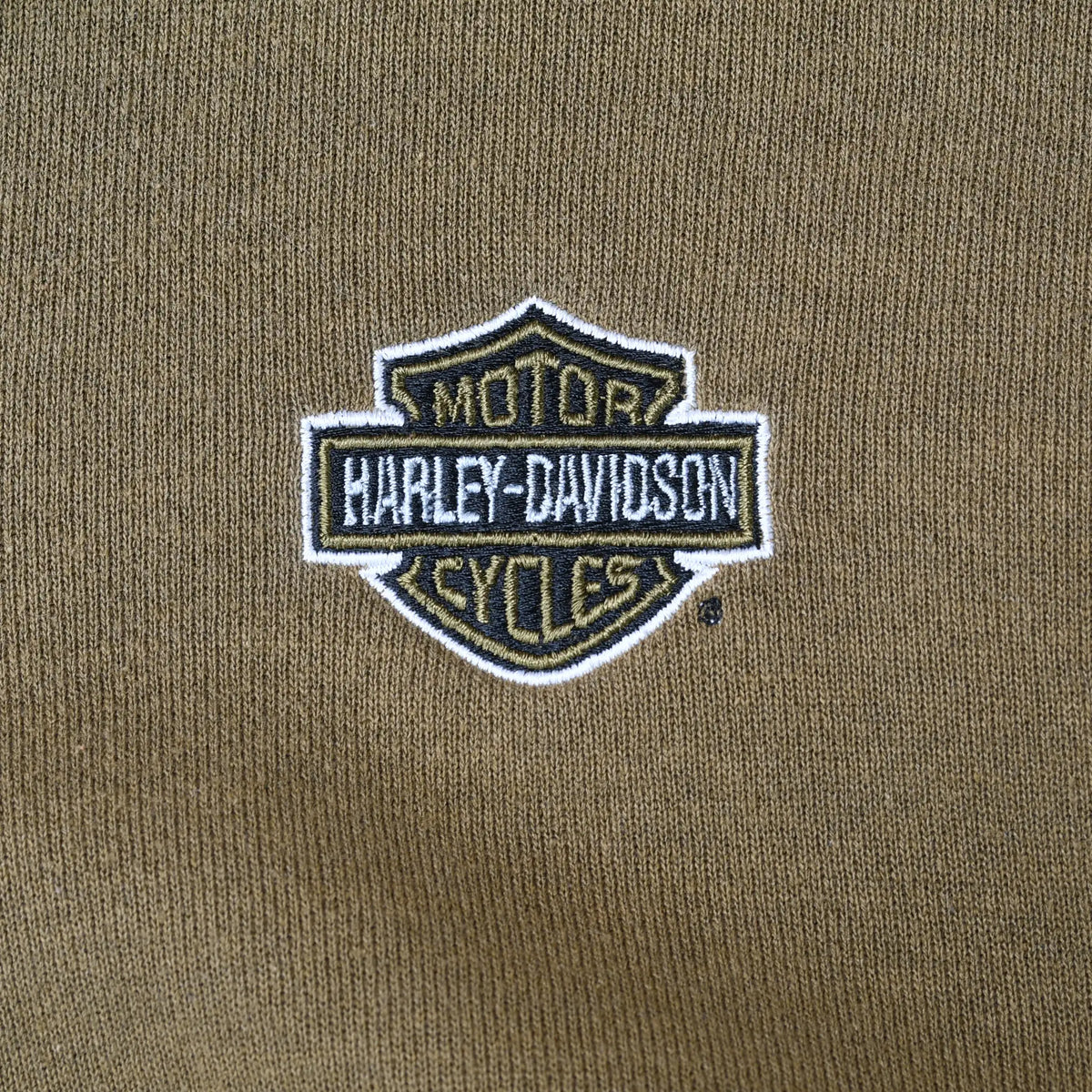 Close-up of Harley-Davidson Motor Cycles shield embroidery on khaki green hoodie chest