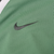 Close-up of dark gray embroidered Nike Swoosh on green jacket chest