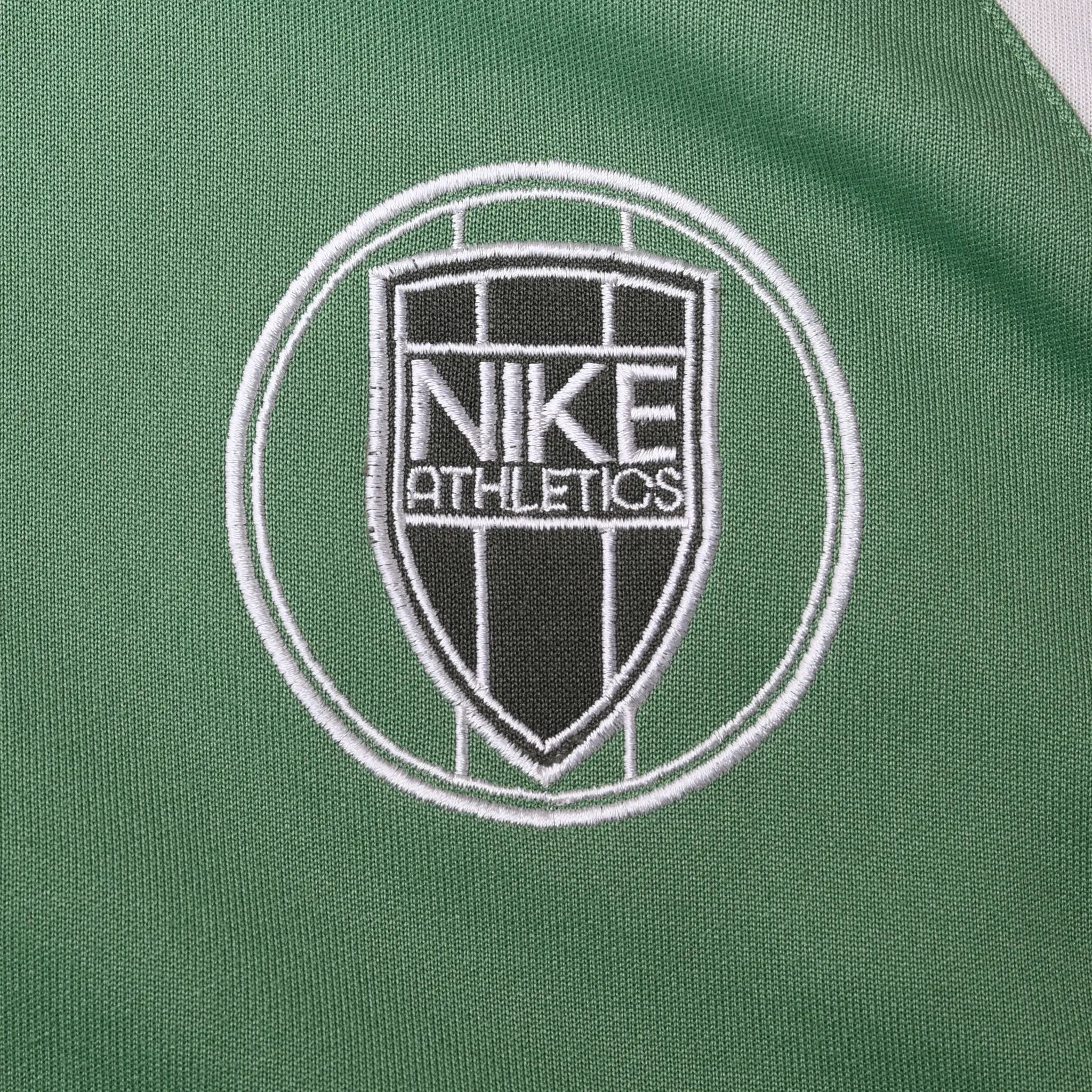 Close-up of black and white Nike Athletics crest embroidery on green jacket chest