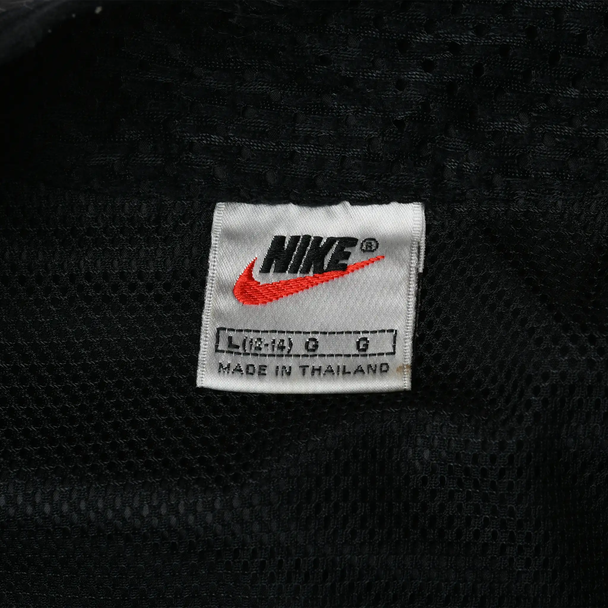Nike L/G neck label with red Swoosh and Made in Thailand text on black mesh lining