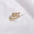 Close-up of gold Nike logo embroidery on white jacket fabric
