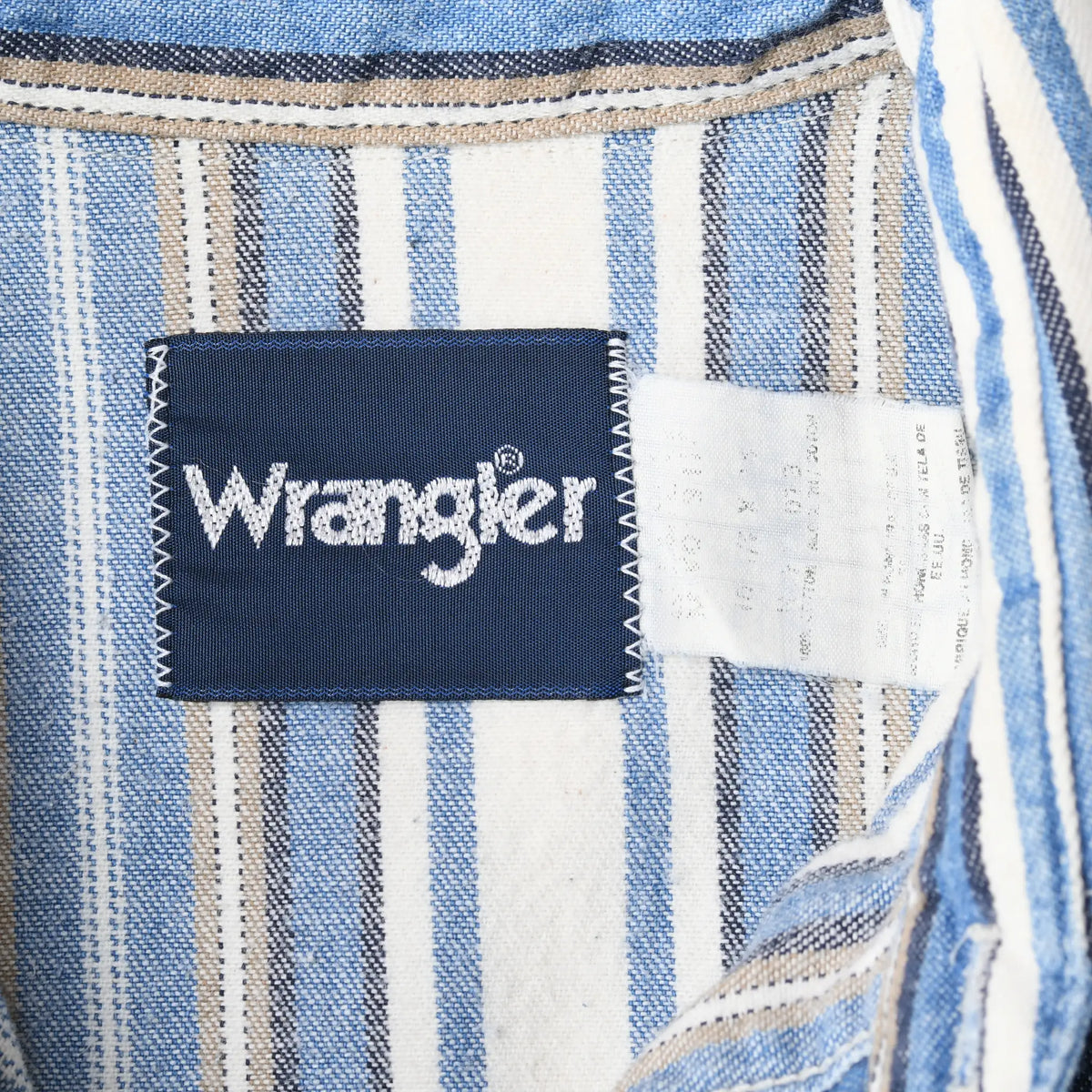 Close-up of Wrangler neck label and faded care tag inside the striped shirt collar
