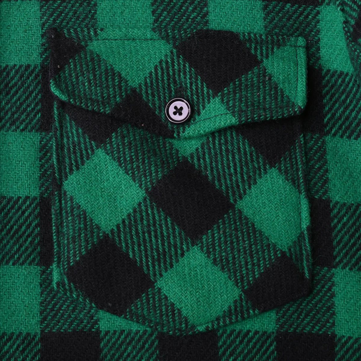 Close-up of button-flap chest pocket on green and black plaid flannel shirt
