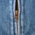 Close-up of metal zipper pull and teeth on blue denim jacket