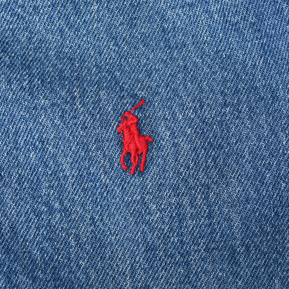 Close-up of red Polo pony embroidery on blue denim jacket chest