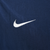 Close-up of white embroidered Nike Swoosh on navy windbreaker fabric