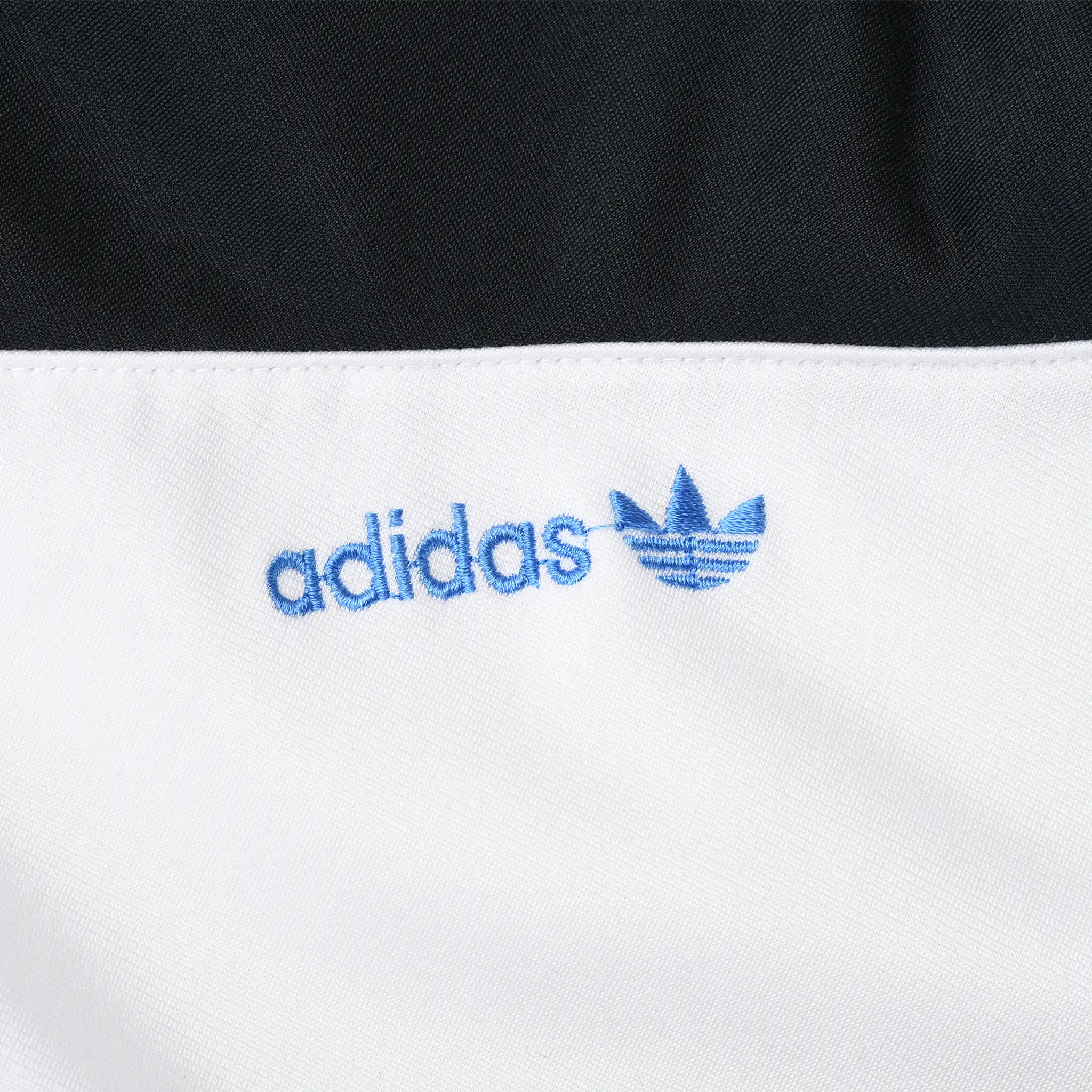 Close-up of blue Adidas trefoil logo embroidered on white front panel