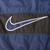 Close-up of oversized navy and white Nike Swoosh on the black back panel