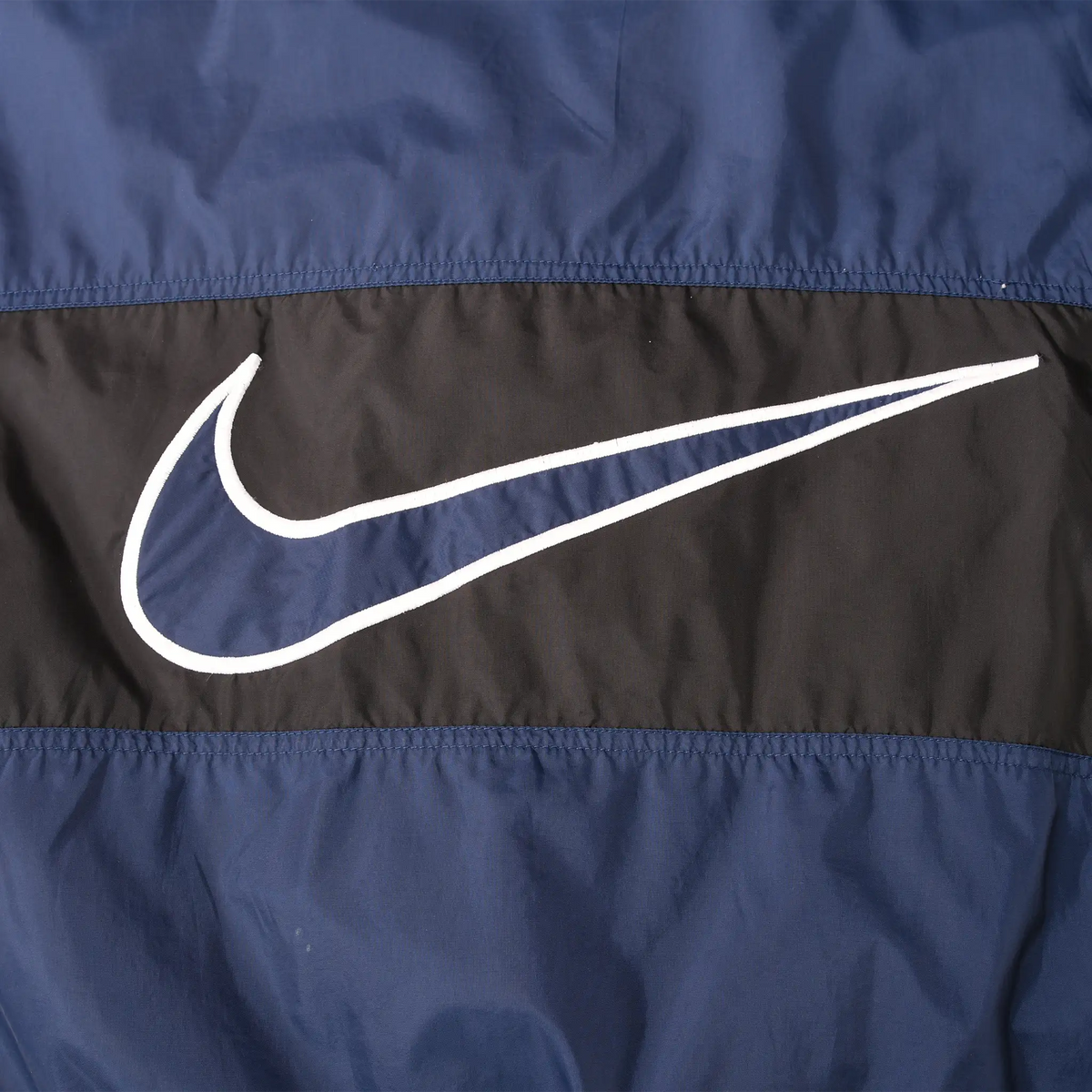 Close-up of oversized navy and white Nike Swoosh on the black back panel