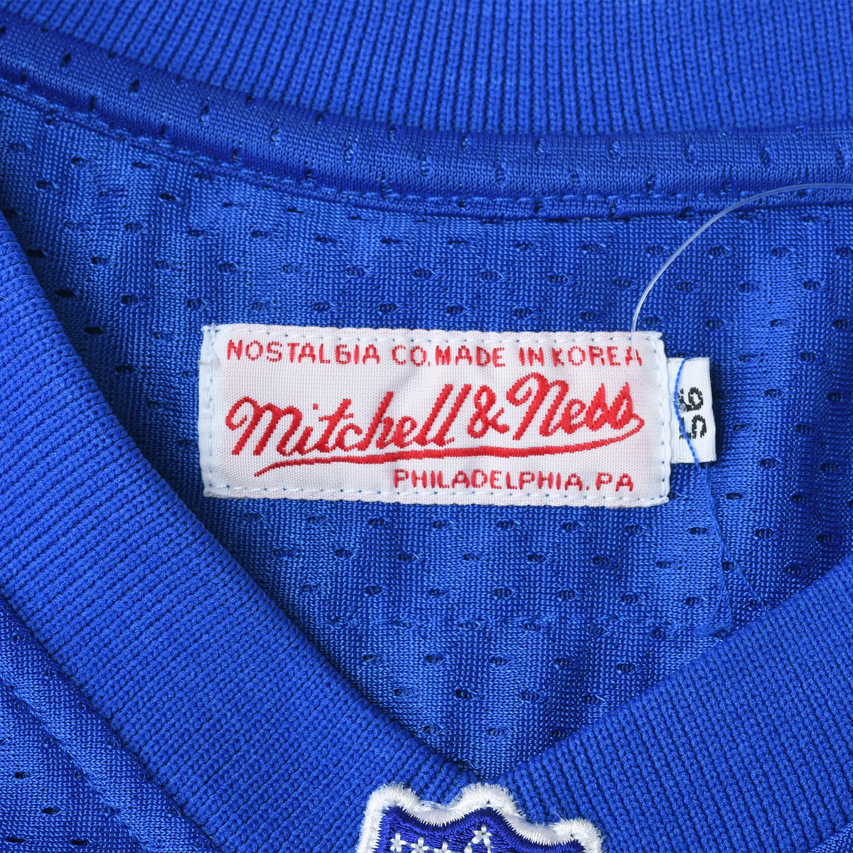 Mitchell & Ness neck label and 3XL size tag on blue mesh jersey fabric