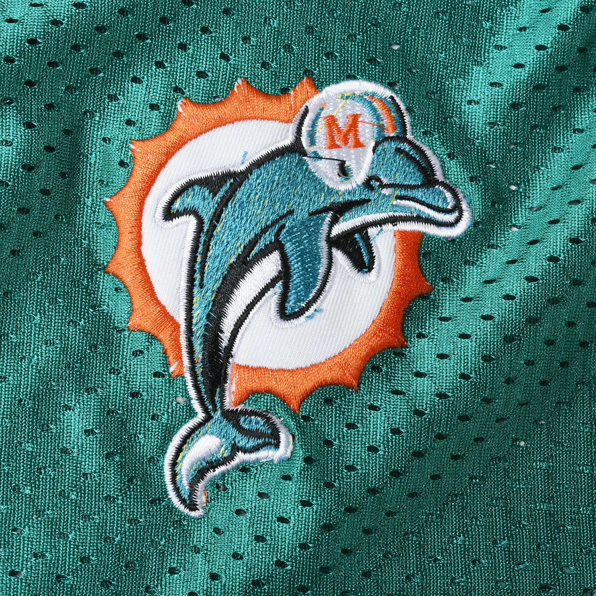 Close-up of embroidered Miami Dolphins logo on aqua mesh jersey fabric