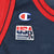 Close-up of embroidered Champion and USA Basketball logos on navy jersey chest