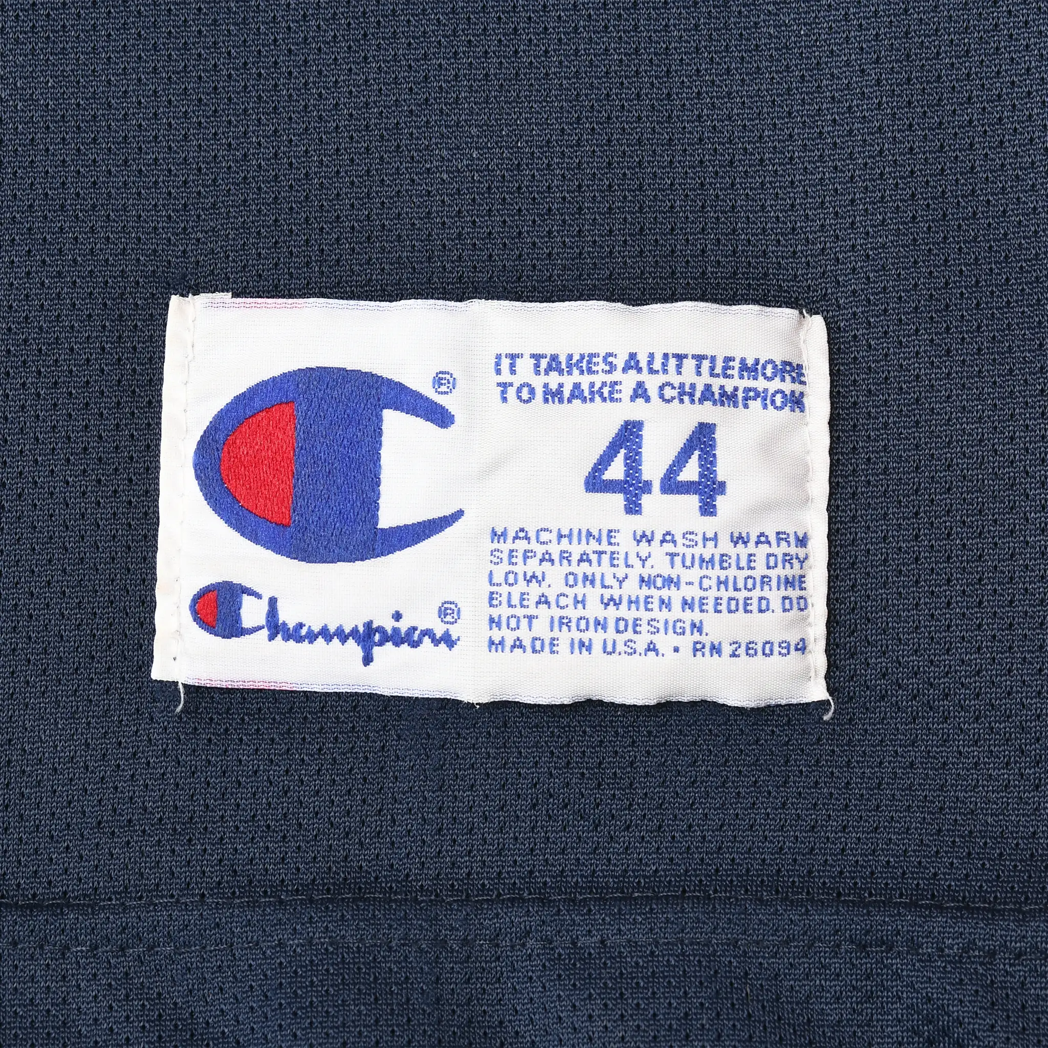 Close-up of Champion size 44 care label sewn inside navy basketball jersey
