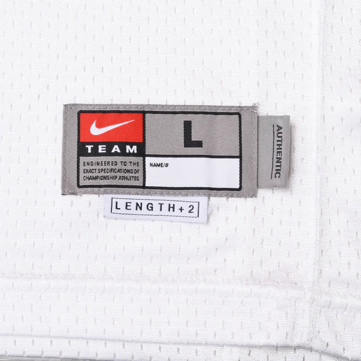 Close-up of Nike Team size large jock tag with Length +2 label on white jersey fabric