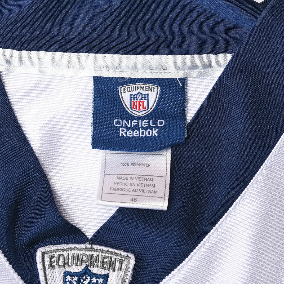 Close-up of NFL Equipment Reebok neck tag and navy V-neck collar