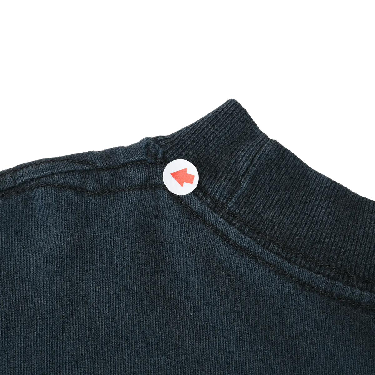 Close-up of black ribbed collar and shoulder seam with arrow marker indicating stitching detail