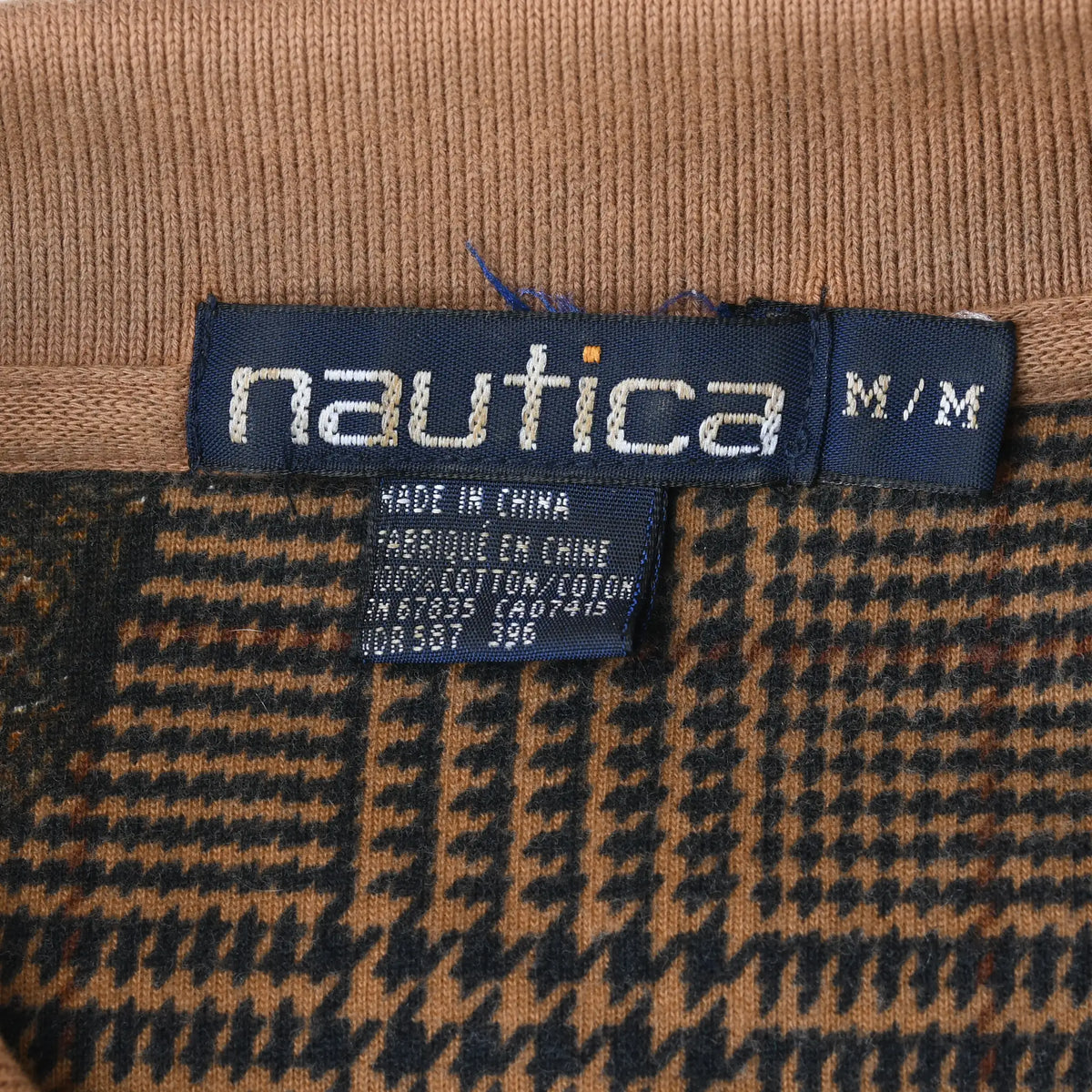 Nautica M size neck label against tan ribbed collar and brown plaid fabric