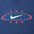 Close-up of front Nike Swoosh graphic with red oval, blue stripes, and six yellow stars
