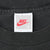 Close-up of white Nike neck tag marked size S and Made in U.S.A. on black fabric