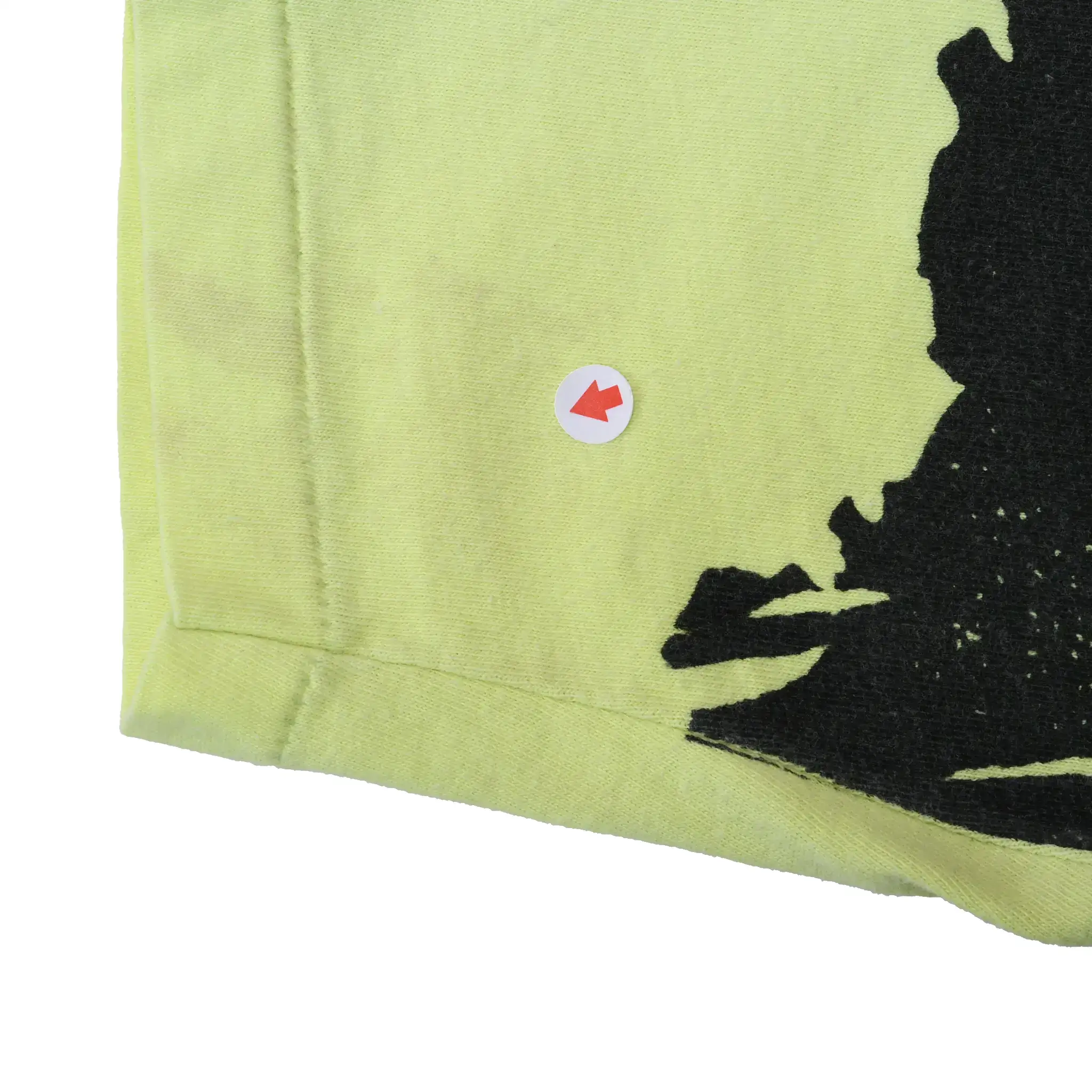 Close-up of lower hem with arrow marker pointing to a small spot beside the black print