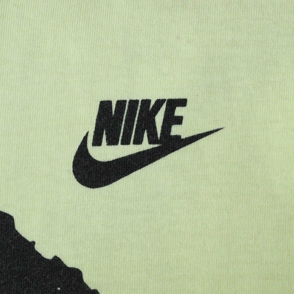 Close-up of black Nike logo and Swoosh printed on neon yellow fabric