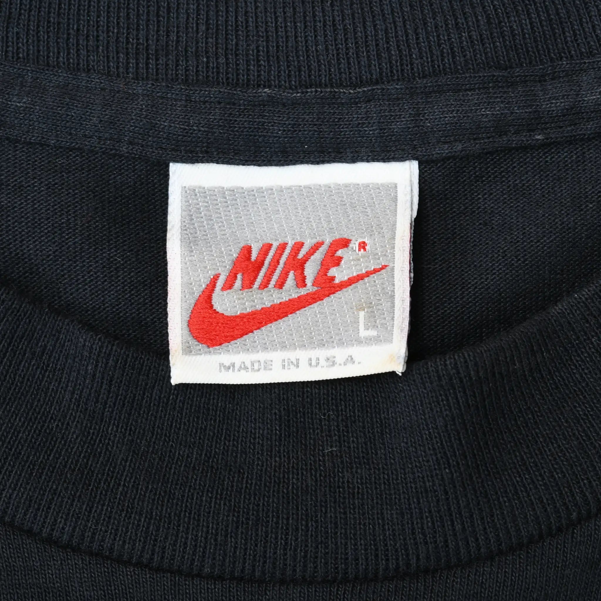 Close-up of white Nike neck tag marked L and Made in U.S.A. inside black T-shirt