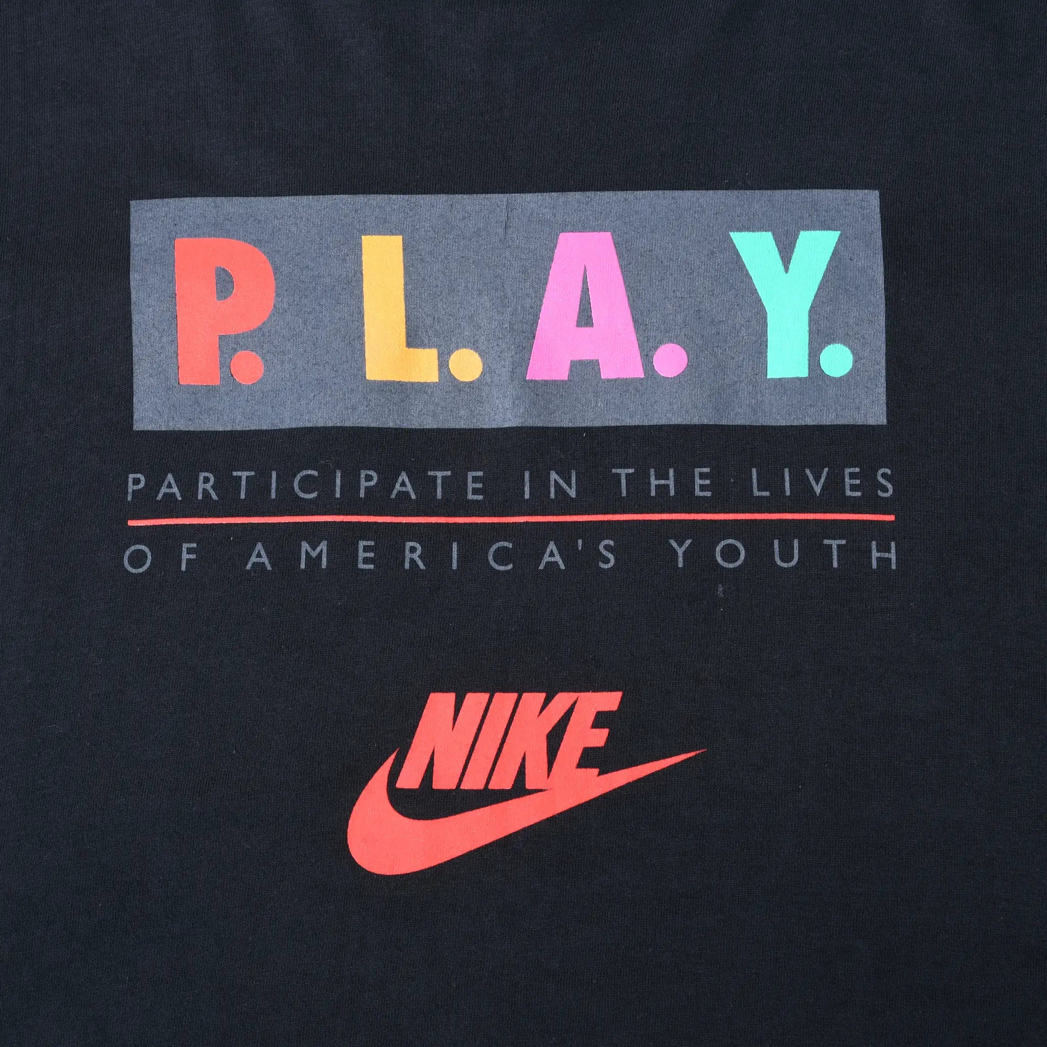 Close-up of multicolor P.L.A.Y. chest print with youth participation text and red Nike logo