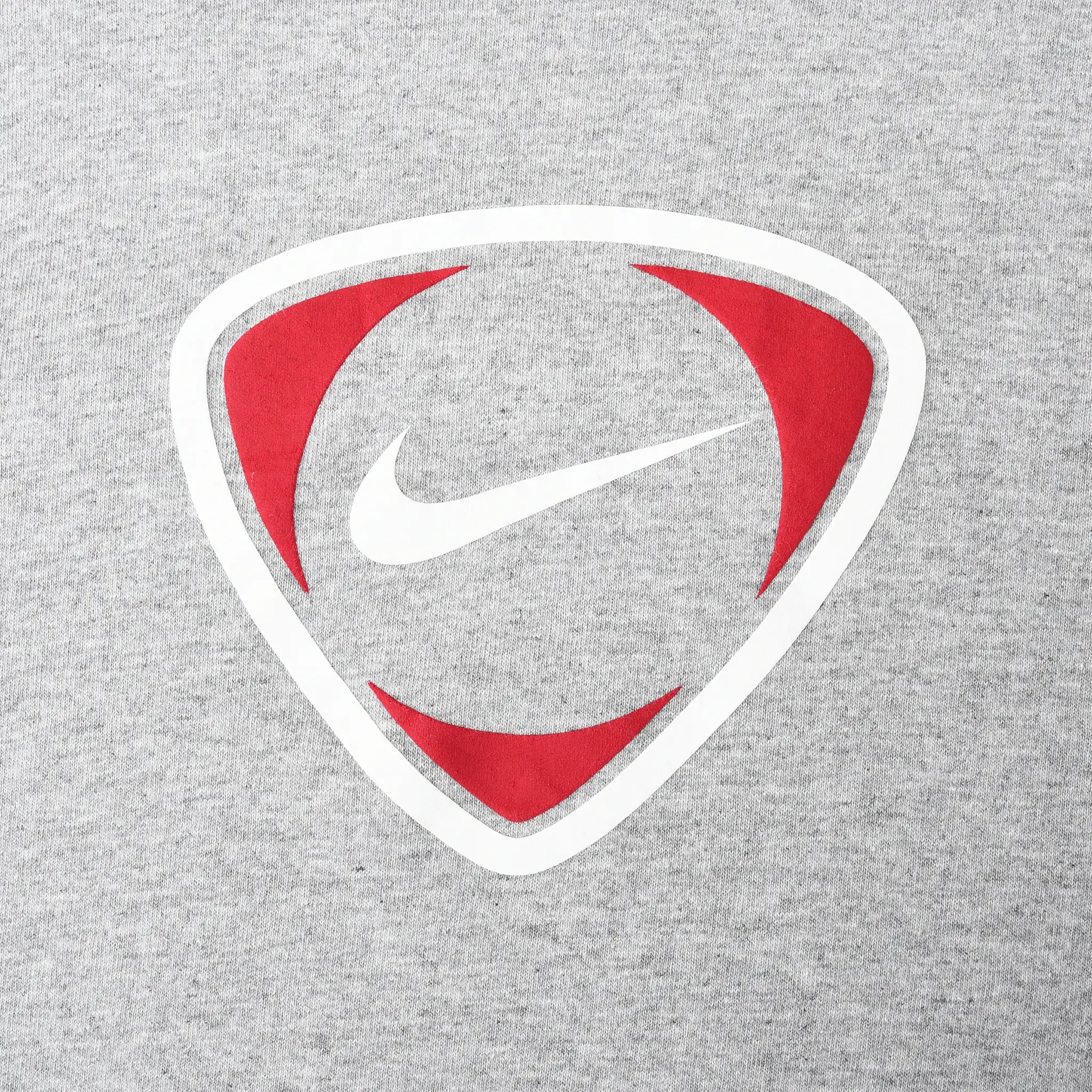 Close-up of red and white Nike Swoosh shield graphic on grey fabric