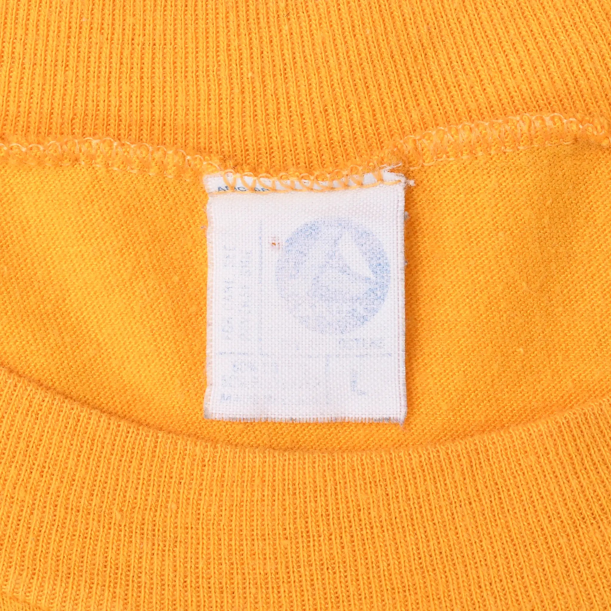 Close-up of faded white neck tag and ribbed collar on gold T-shirt
