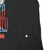 Close-up of black front fabric beside the Lynyrd Skynyrd print, with a small spot marked by an arrow