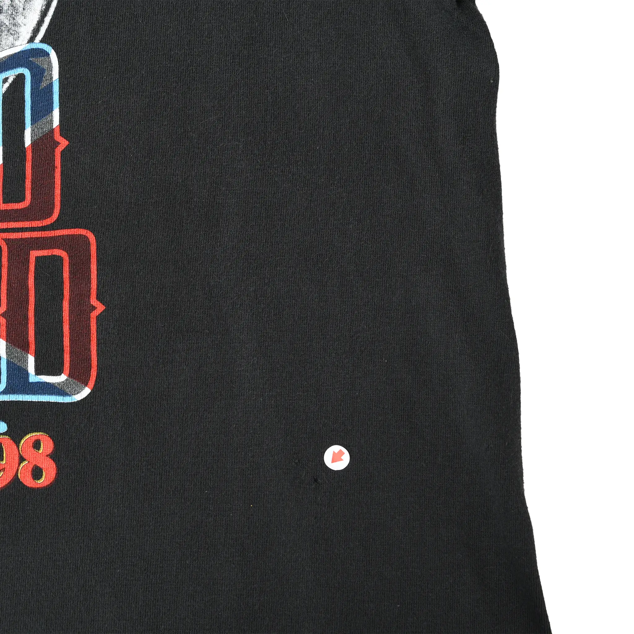 Close-up of black front fabric beside the Lynyrd Skynyrd print, with a small spot marked by an arrow