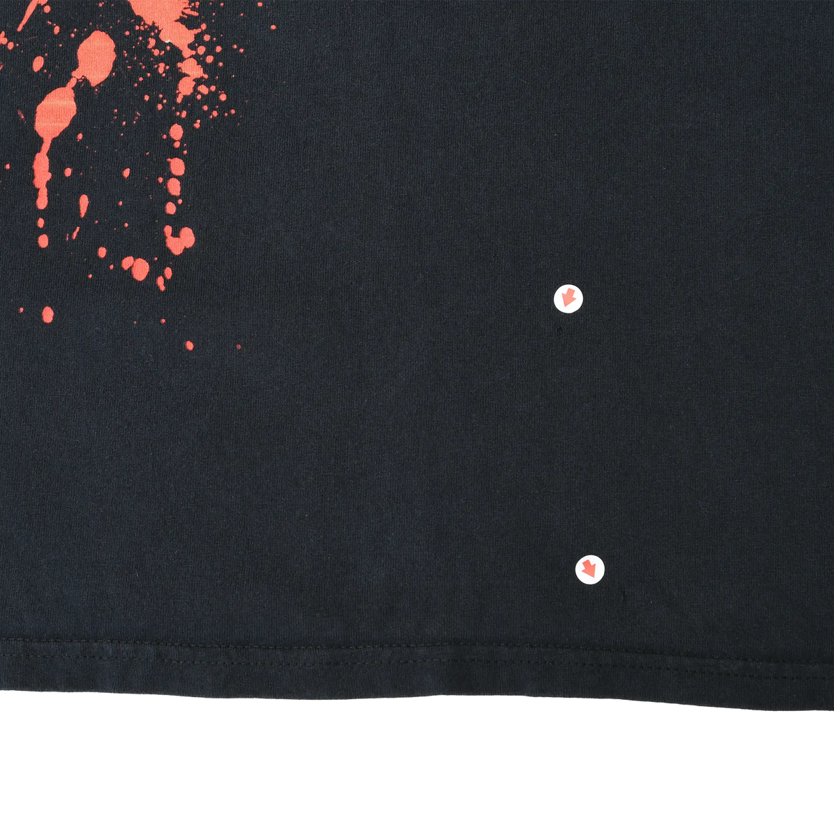 Close-up of lower front hem showing two small holes beside the red splatter print