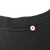 Close-up of the black T-shirt collar seam with arrow marking the stitching