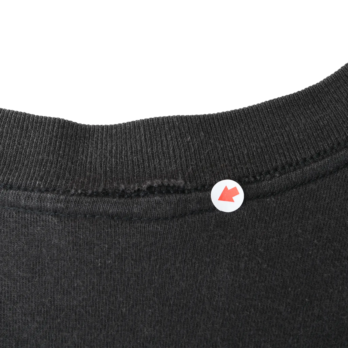 Close-up of the black T-shirt collar seam with arrow marking the stitching