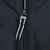 Close-up of black windbreaker front zipper with black-and-white striped fabric pull