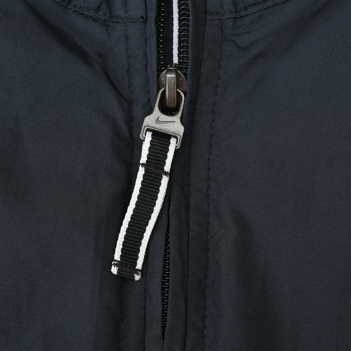 Close-up of black windbreaker front zipper with black-and-white striped fabric pull