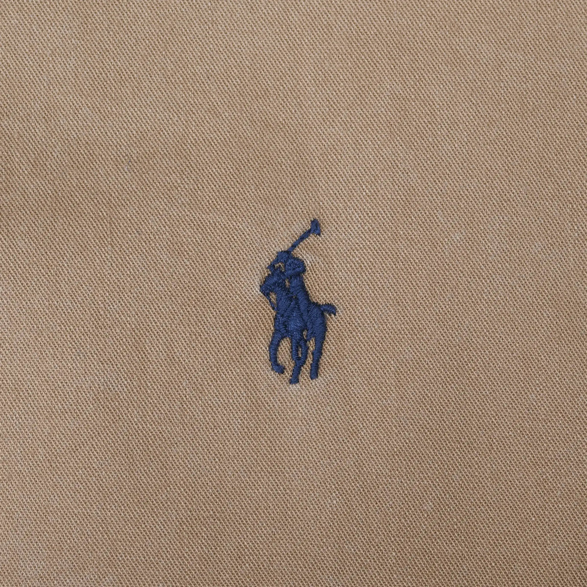 Close-up of navy Ralph Lauren Polo pony embroidery on brown fabric