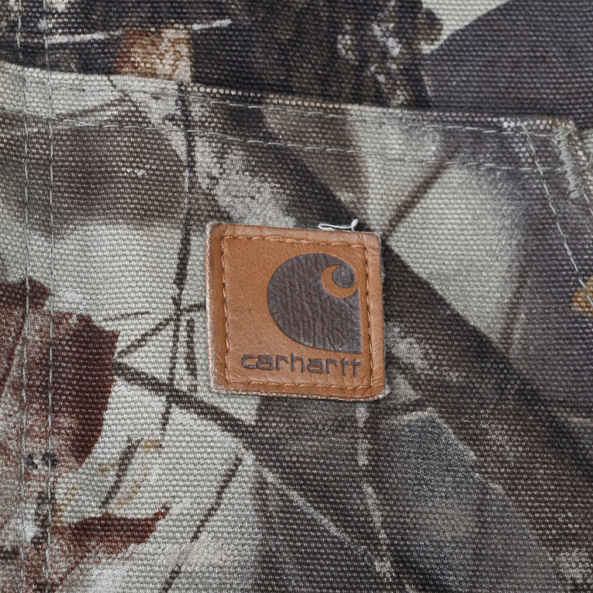 Close-up of square Carhartt logo patch sewn onto a front pouch pocket