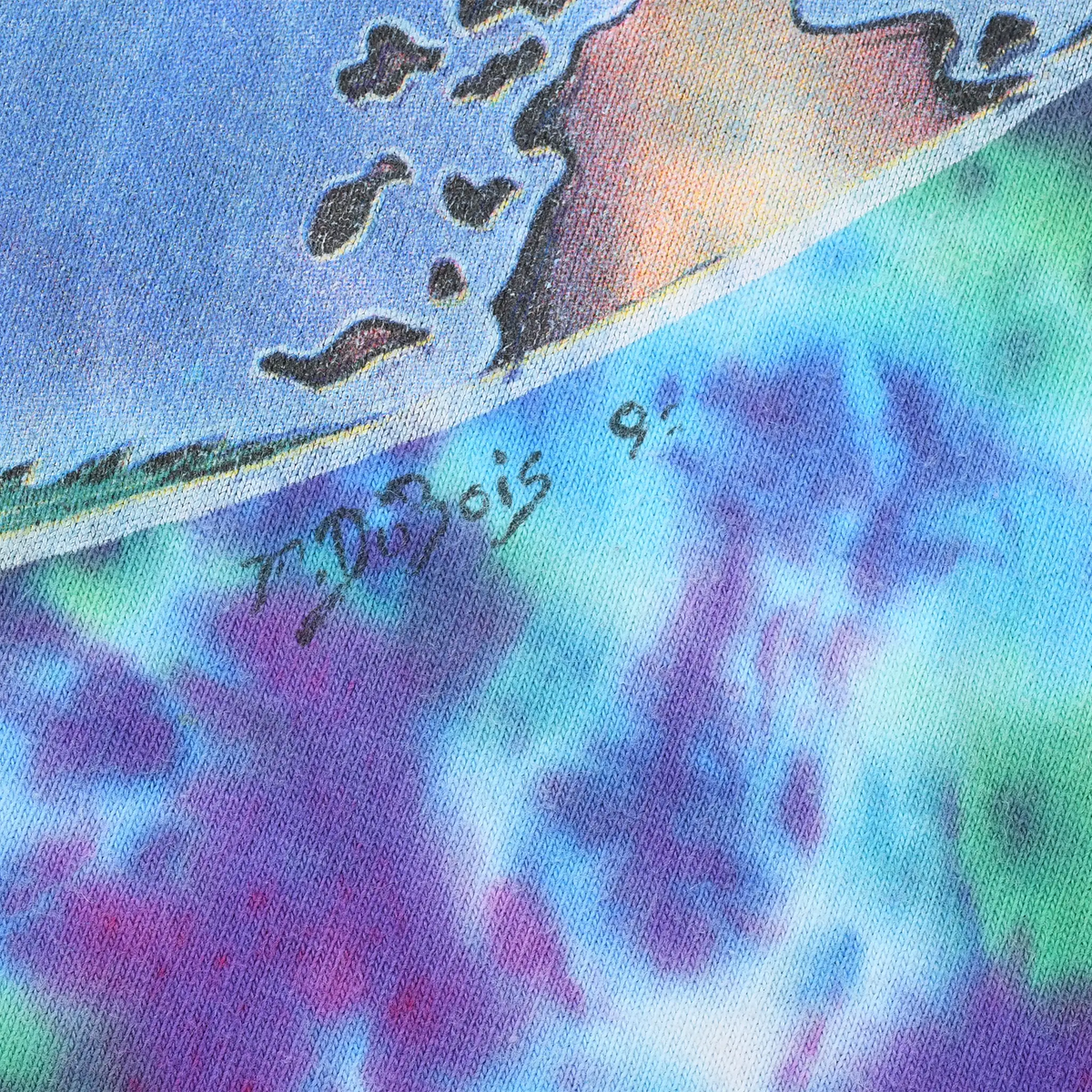Close-up of artist signature beside the printed graphic on tie-dye fabric