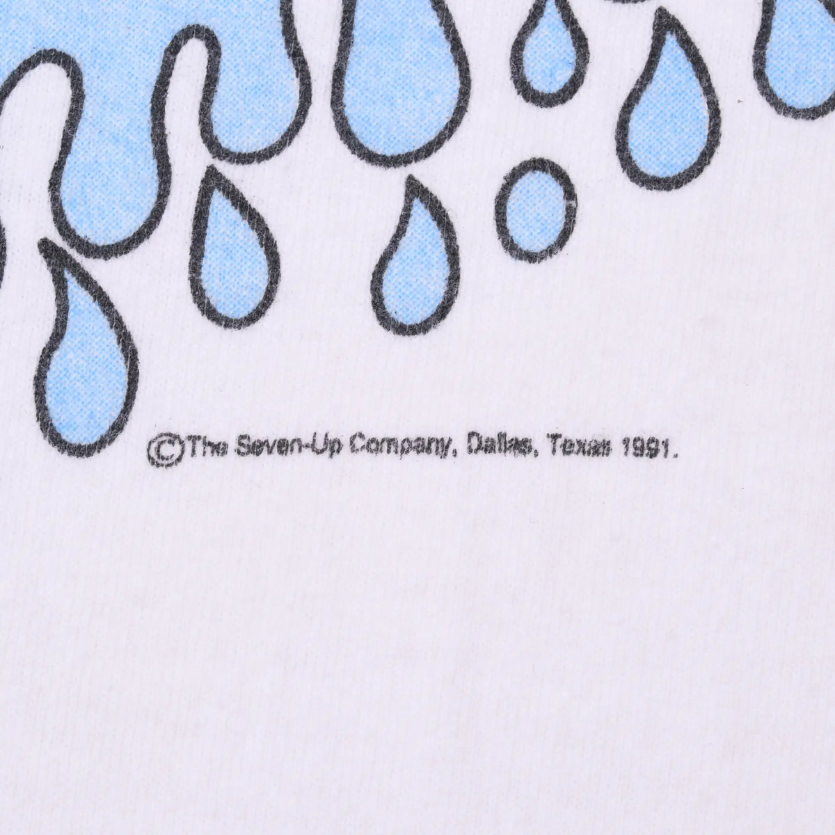 Close-up of blue water-drop print and Seven-Up Company, Dallas, Texas 1991 copyright text