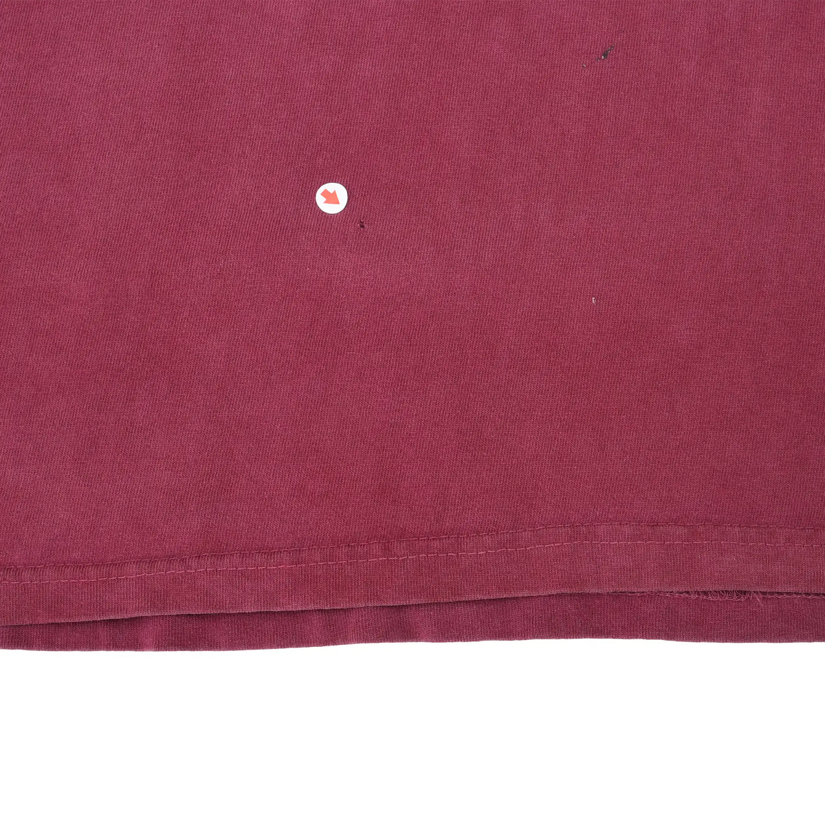 Burgundy fabric near the bottom hem with arrow marking a small spot