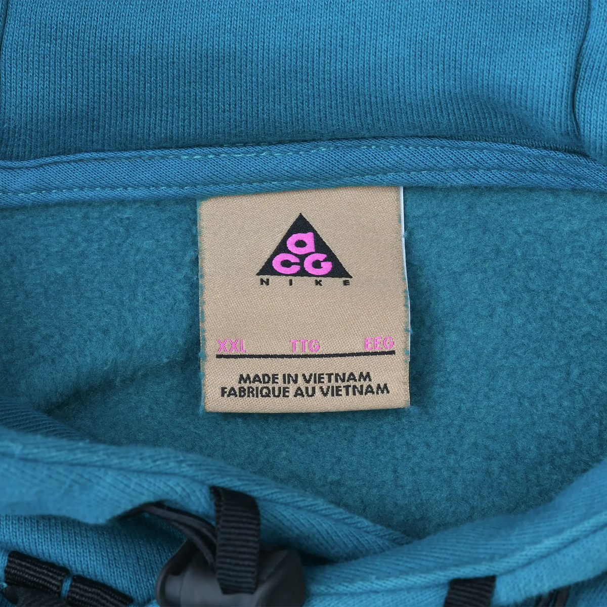 Nike ACG neck label inside teal blue hoodie showing XXL sizing and Made in Vietnam text